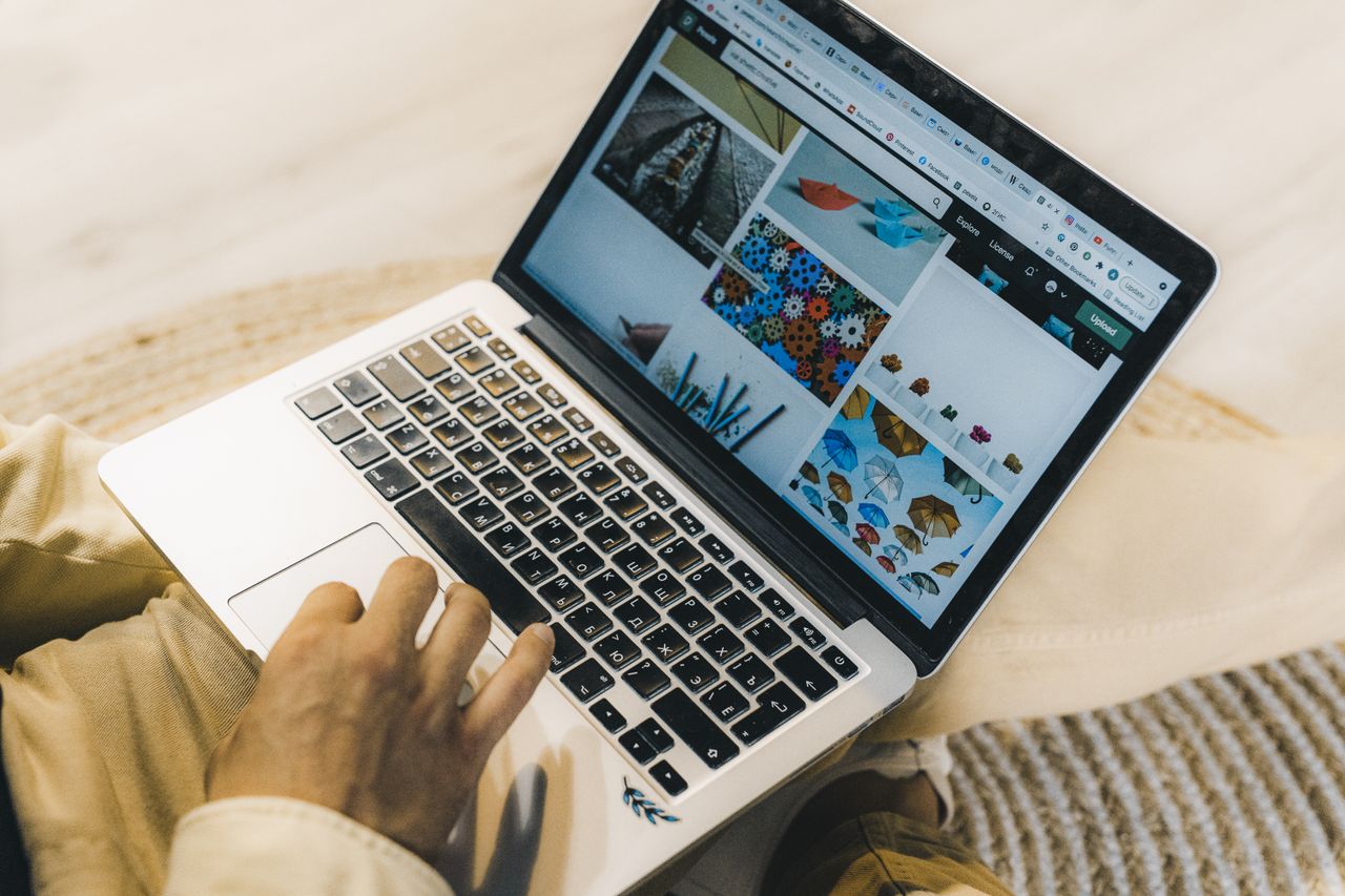 Une personne utilisant un ordinateur portable pour explorer des sites de photos libres de droits. Travail en freelance dans un environnement confortable.